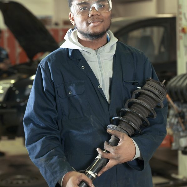 student-carrying-car-part-in-garage.jpg